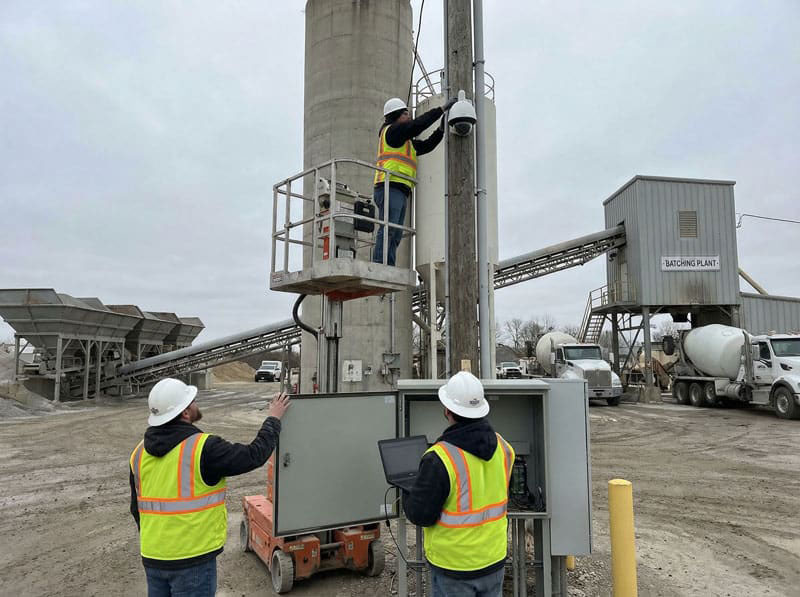 Technicians installing a security camera at a concrete batch plant