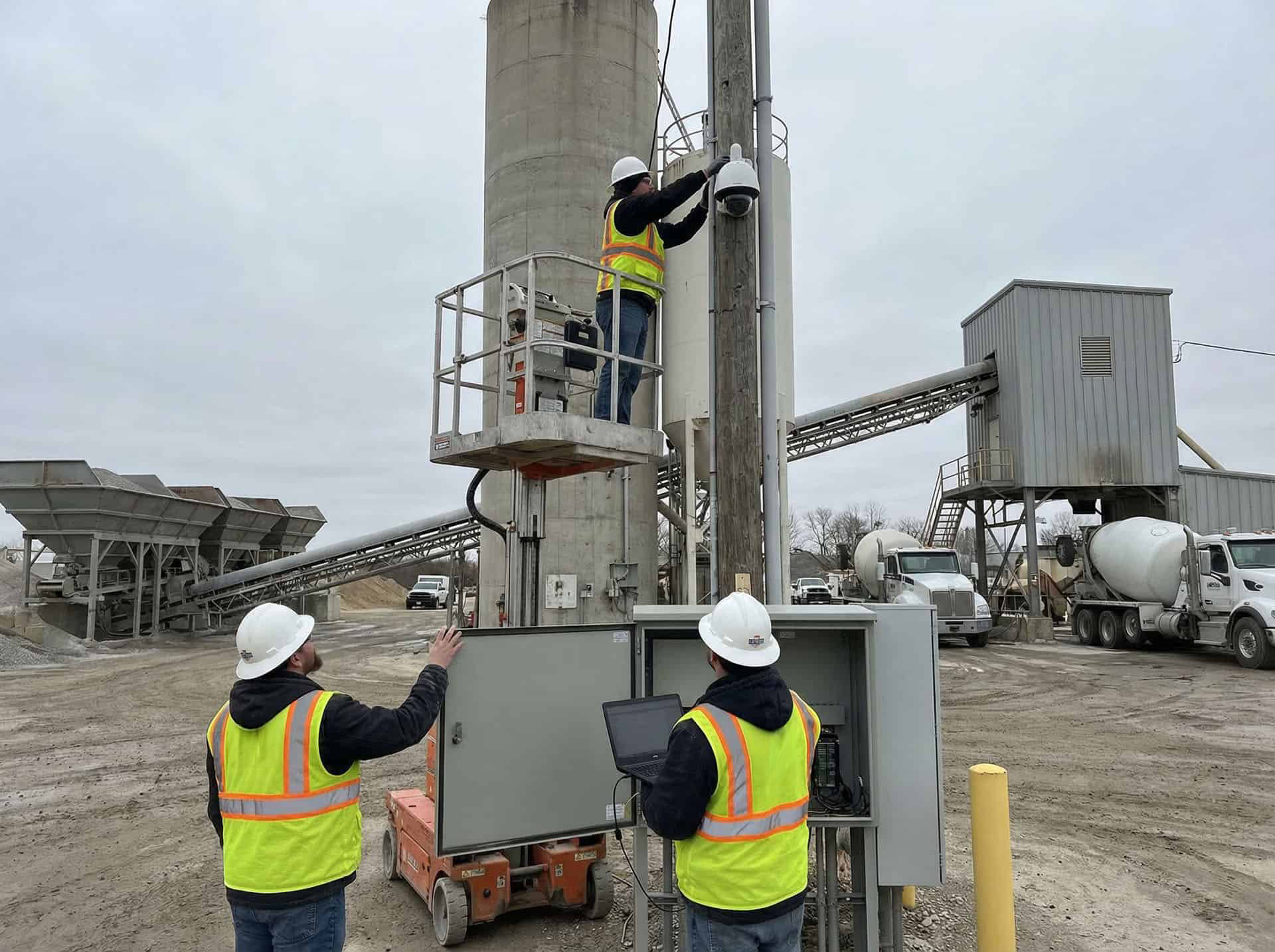 Technicians installing a security camera at a concrete batch plant